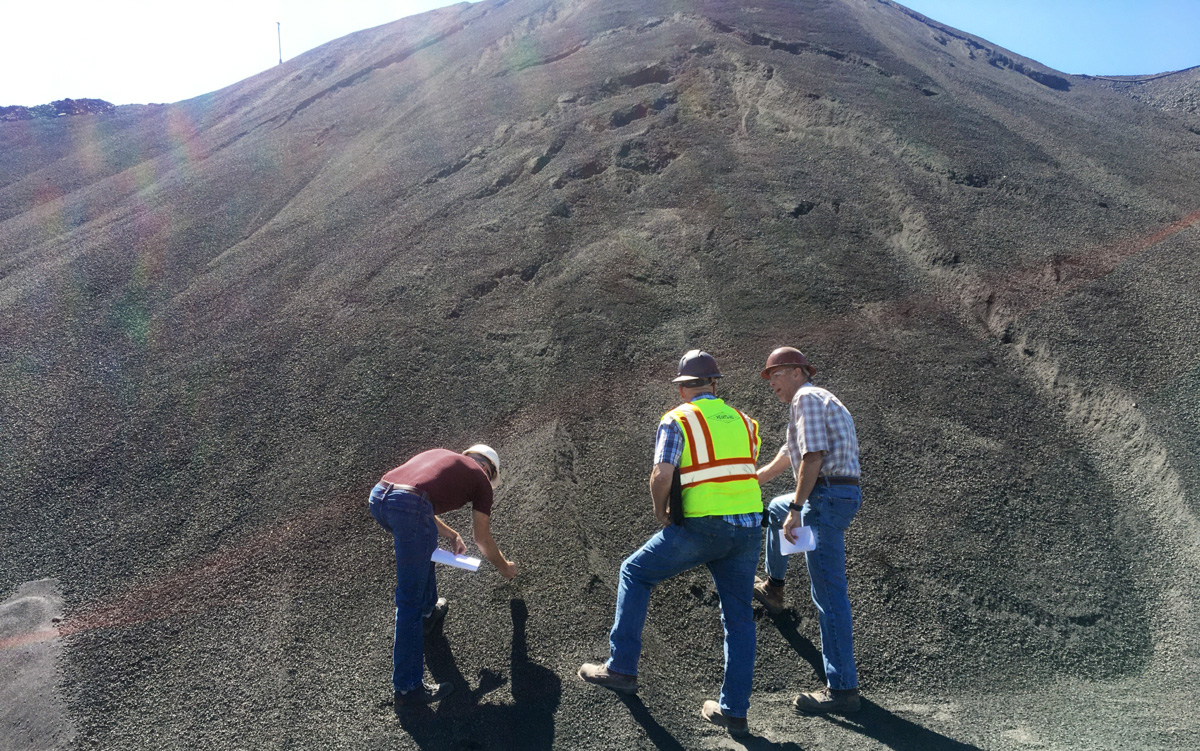 Workers standing in front of mound of aggregate